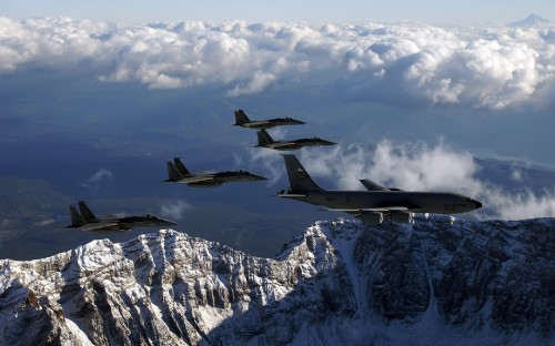 Image black fighter plane flying over snow covered mountain during daytime