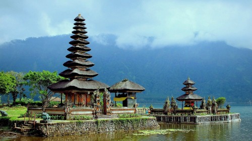 Image brown and green temple near body of water during daytime