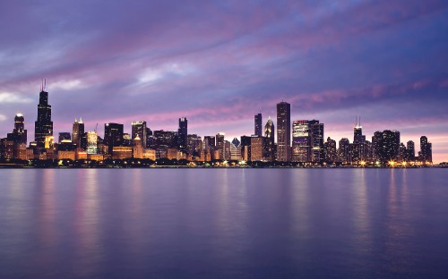 Image city skyline across body of water during night time