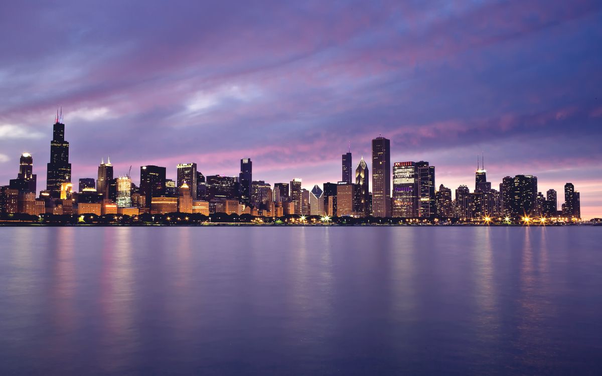 city skyline across body of water during night time