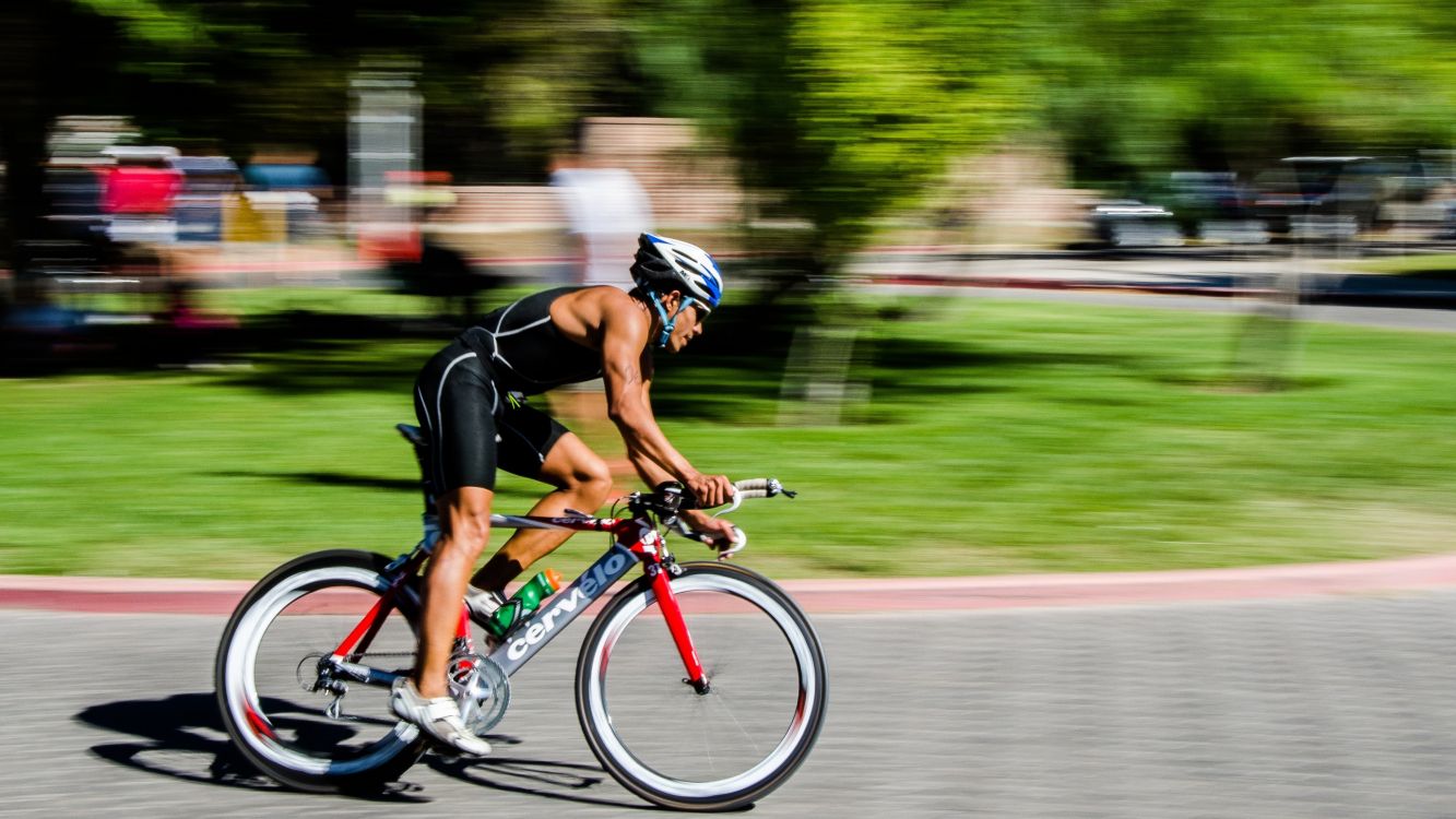 man in black shirt riding on red and black road bike