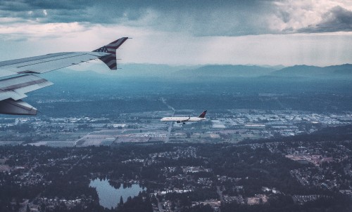 Image white and red airplane flying over city during daytime