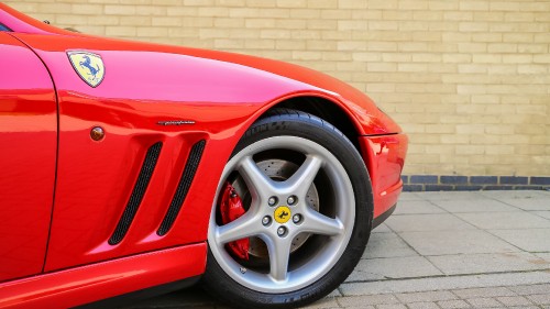 Image red car parked beside brown brick wall