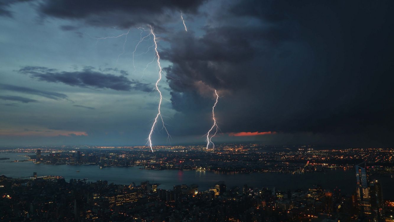 city skyline under white clouds and blue sky during night time