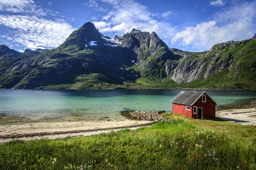 Image brown wooden house near body of water and mountain during daytime