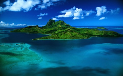 Image green mountain beside blue sea under blue sky and white clouds during daytime