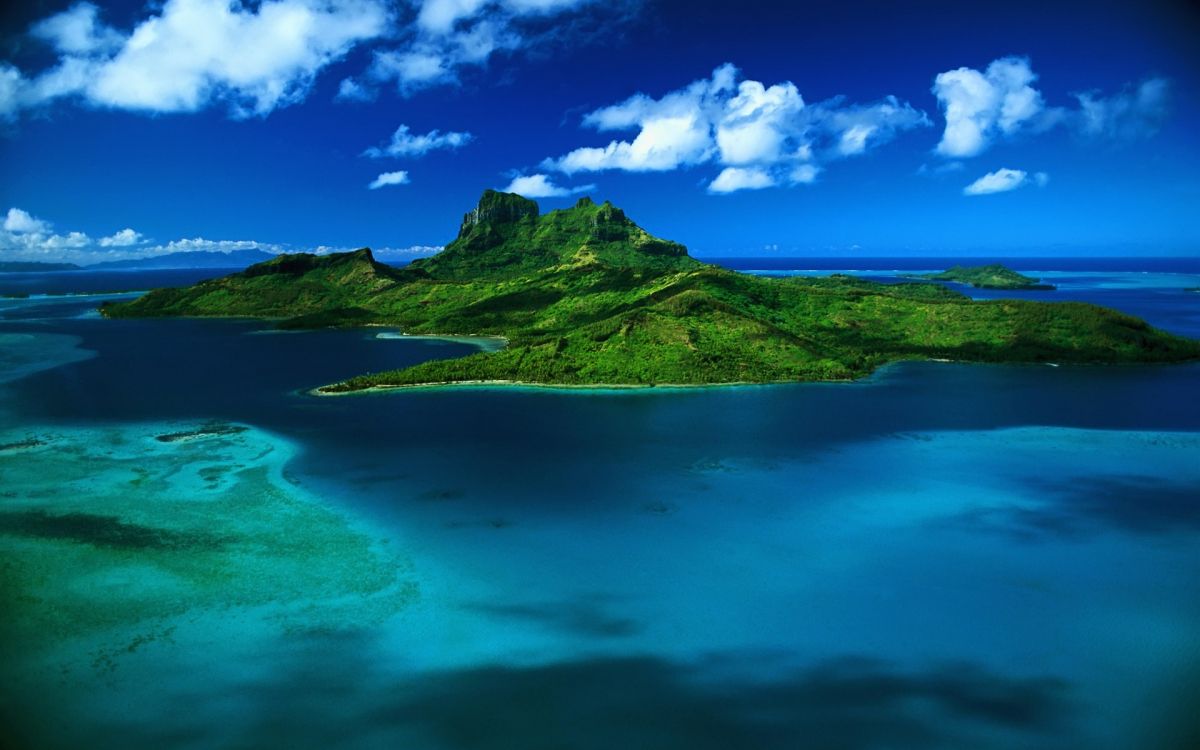 green mountain beside blue sea under blue sky and white clouds during daytime