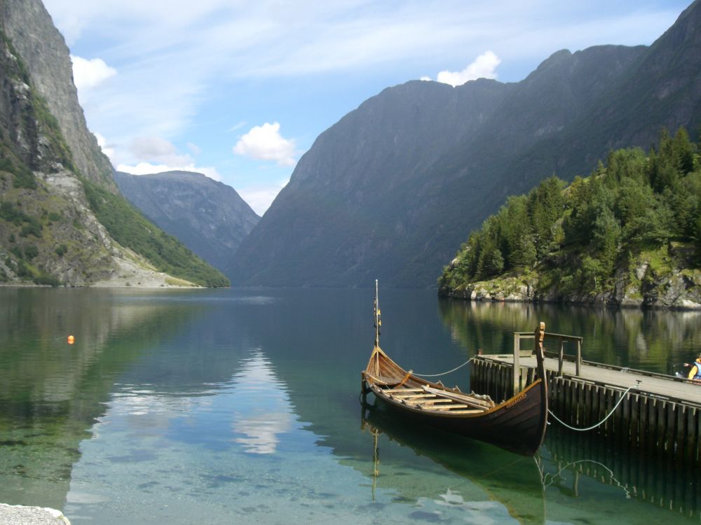 brown boat on lake near green mountains during daytime