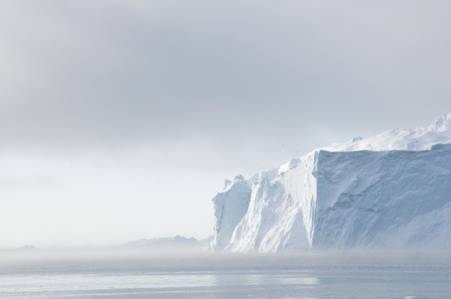 Image snow covered mountain near body of water during daytime