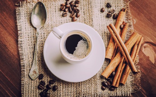 Image white ceramic mug with coffee beside stainless steel spoon