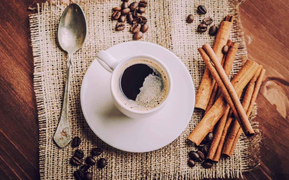 white ceramic mug with coffee beside stainless steel spoon