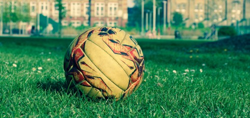 Image brown and black soccer ball on green grass field during daytime