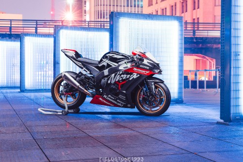 Image black sports bike parked beside white and blue building