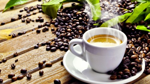 Image white ceramic cup on saucer beside coffee beans