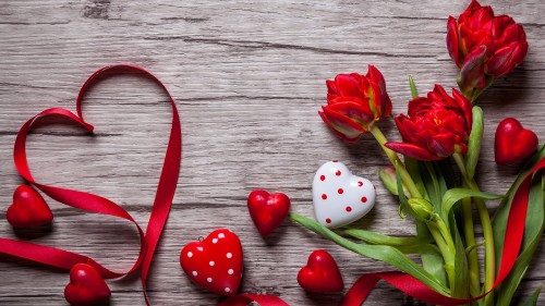 Image red and white ceramic dice beside red tulips