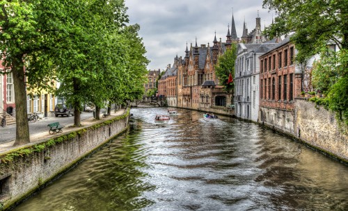 Image river between green trees and brown concrete building during daytime