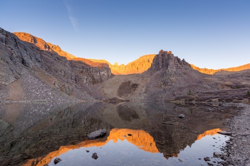 Image brown rocky mountain beside body of water during daytime