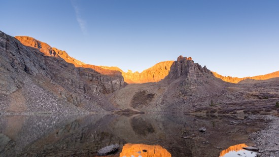 Image brown rocky mountain beside body of water during daytime
