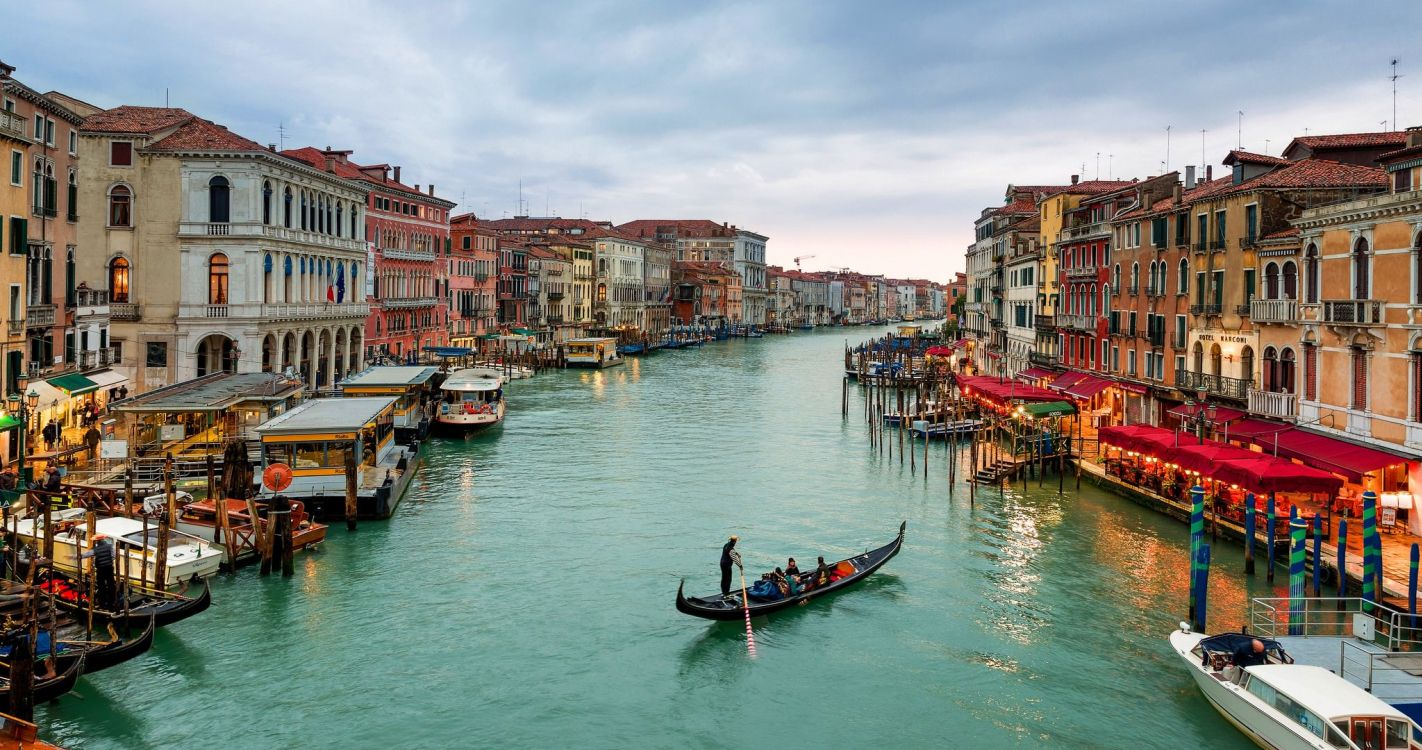 people riding on boat on river near buildings during daytime