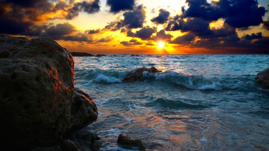 Image rocky shore under cloudy sky during sunset