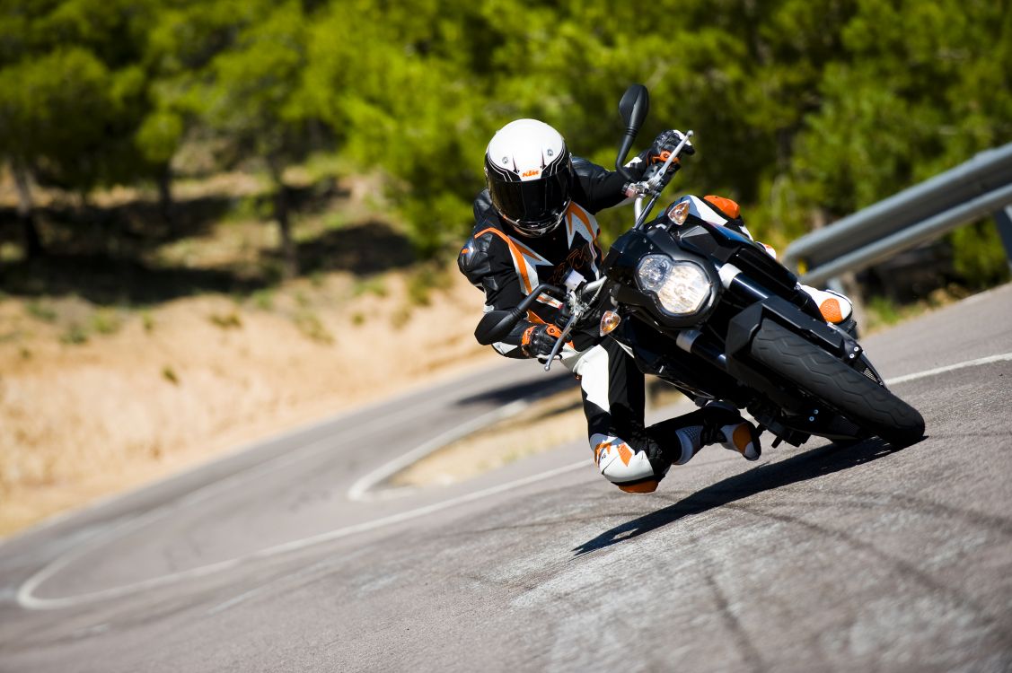 man in black and white motorcycle suit riding motorcycle on road during daytime