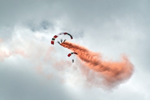 Image person in red parachute under white clouds