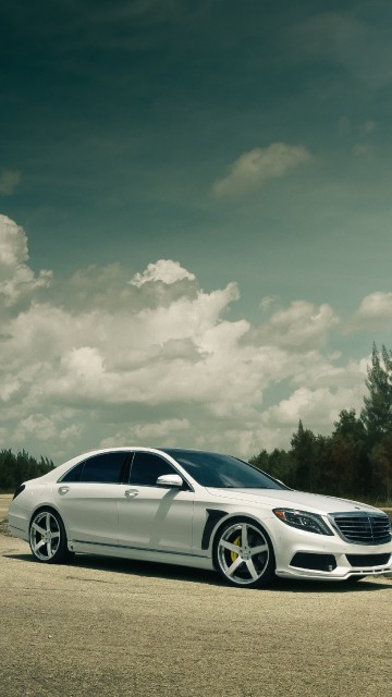 Image white sedan on gray asphalt road under white clouds and blue sky during daytime