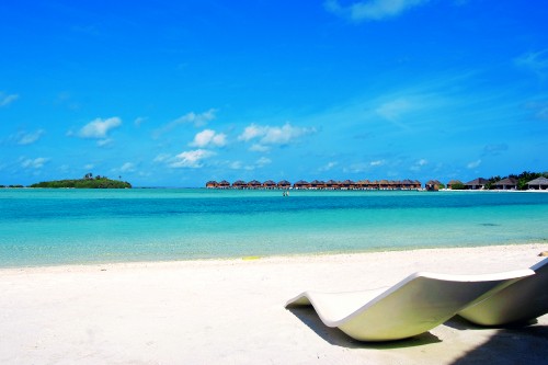 Image white and blue beach chair on white sand near body of water during daytime