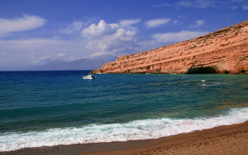 Image white boat on sea near brown rock formation under blue sky during daytime