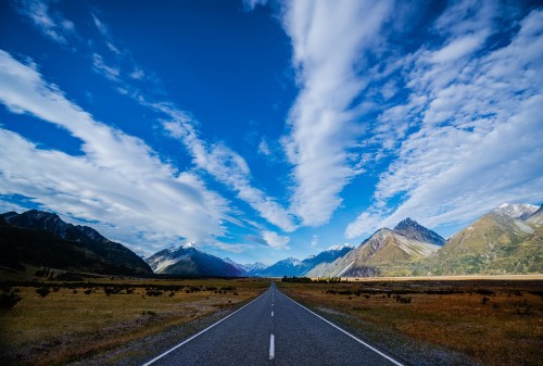 Image gray concrete road near mountain under blue sky during daytime