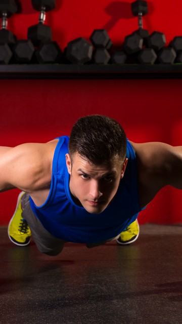 Image man in blue tank top and black shorts doing push up