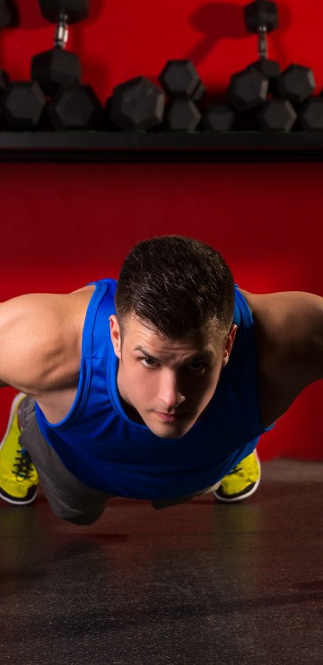 Image man in blue tank top and black shorts doing push up