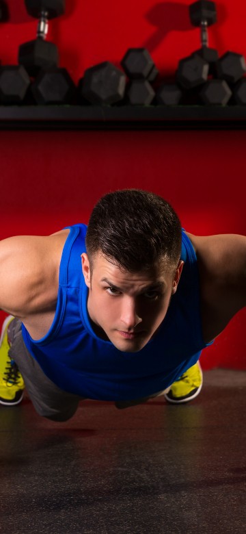 Image man in blue tank top and black shorts doing push up