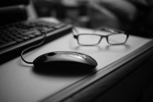 Image black framed eyeglasses on black computer mouse