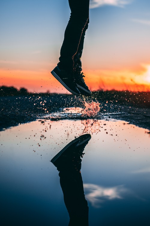 Image person in black pants standing on white sand during sunset