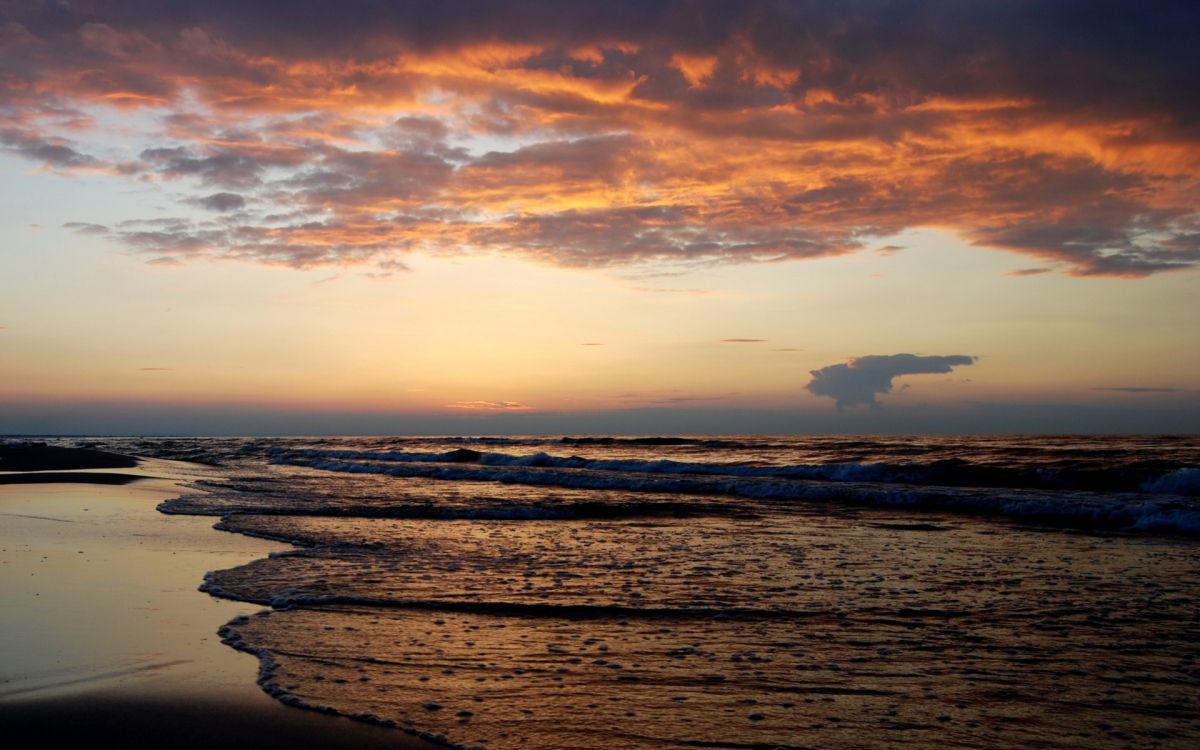 sea waves crashing on shore during sunset