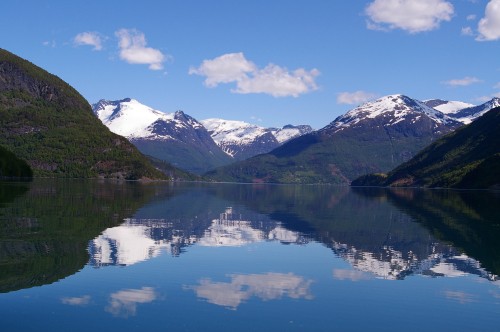 Image snow covered mountain near lake under blue sky during daytime