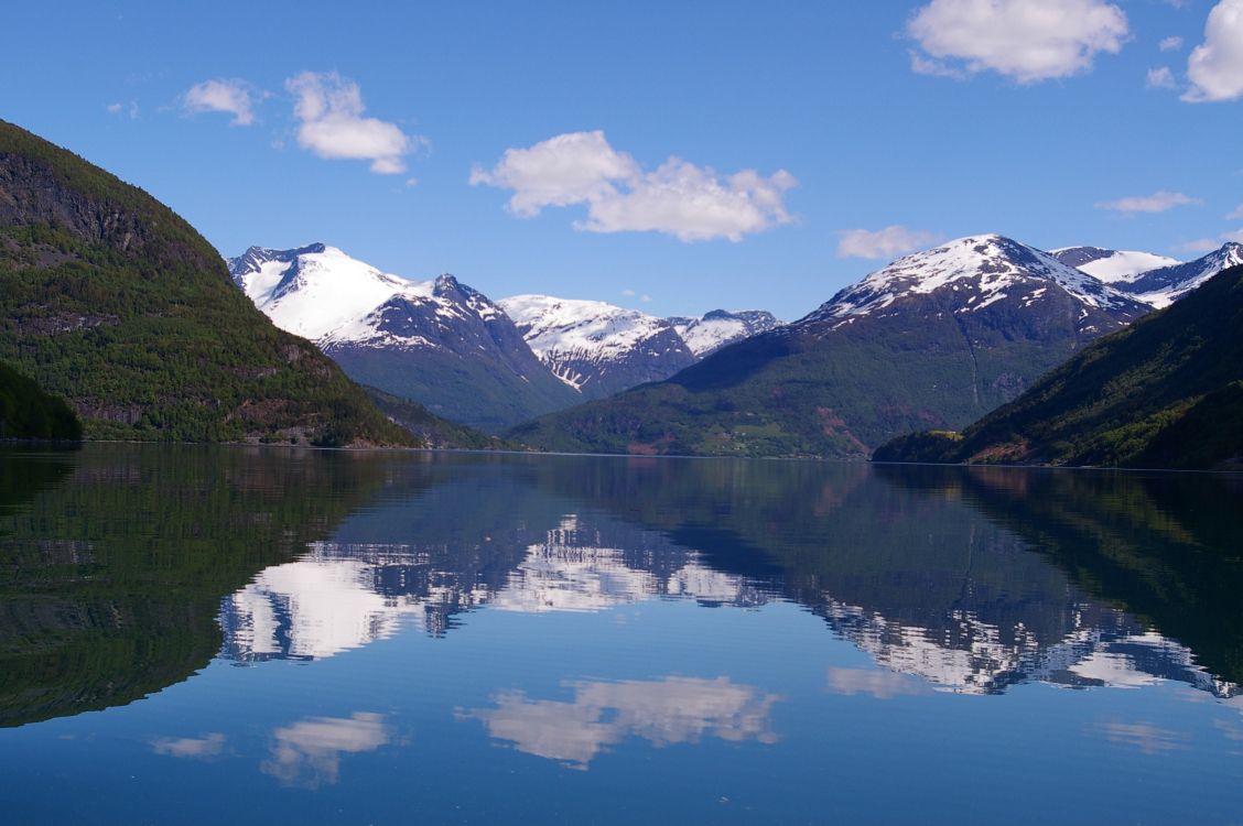 snow covered mountain near lake under blue sky during daytime