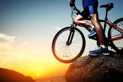 Image man in blue shirt riding black bicycle during sunset