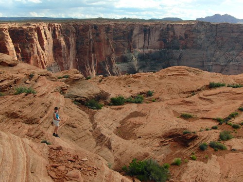 Image woman in white shirt and blue denim jeans walking on brown rocky mountain during daytime