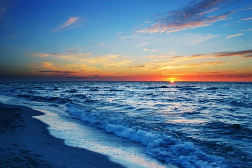 Image ocean waves crashing on shore during sunset