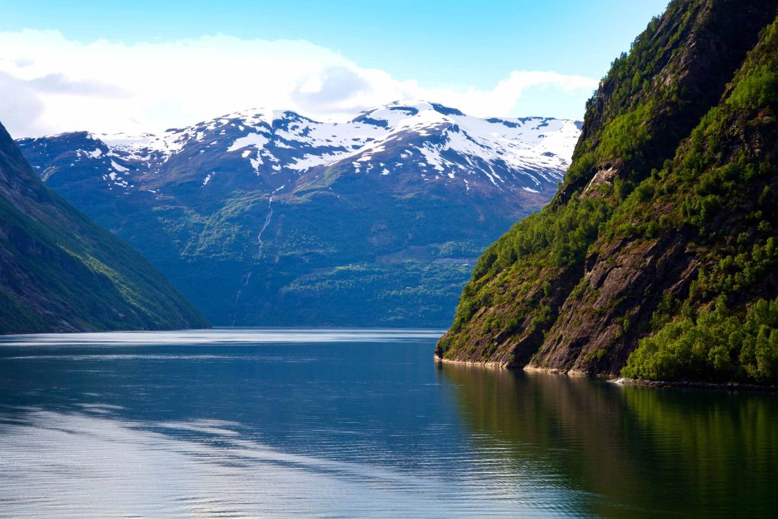 body of water near mountain during daytime