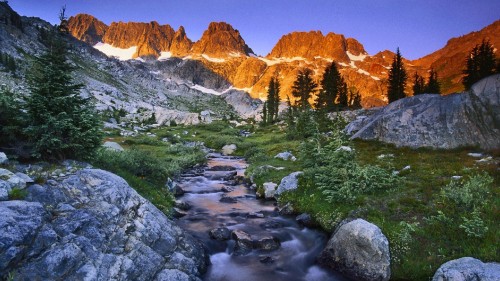 Image brown rocky mountain near green grass field during daytime