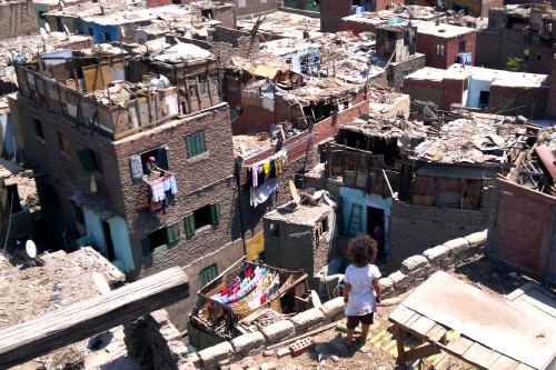 Image man in white t-shirt and blue denim jeans standing on brown concrete building during daytime