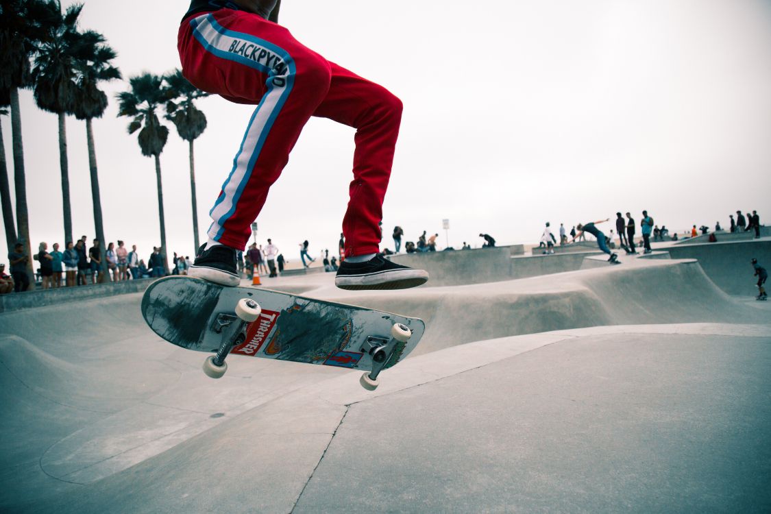Mann in Roten Hosen Und Schwarz-weißen Turnschuhen, Die Skateboard Fahren. Wallpaper in 5760x3840 Resolution