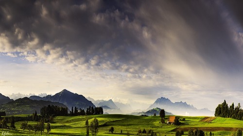 Image green grass field near mountain under cloudy sky during daytime