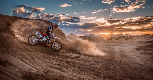 Image man riding motocross dirt bike on brown sand during daytime