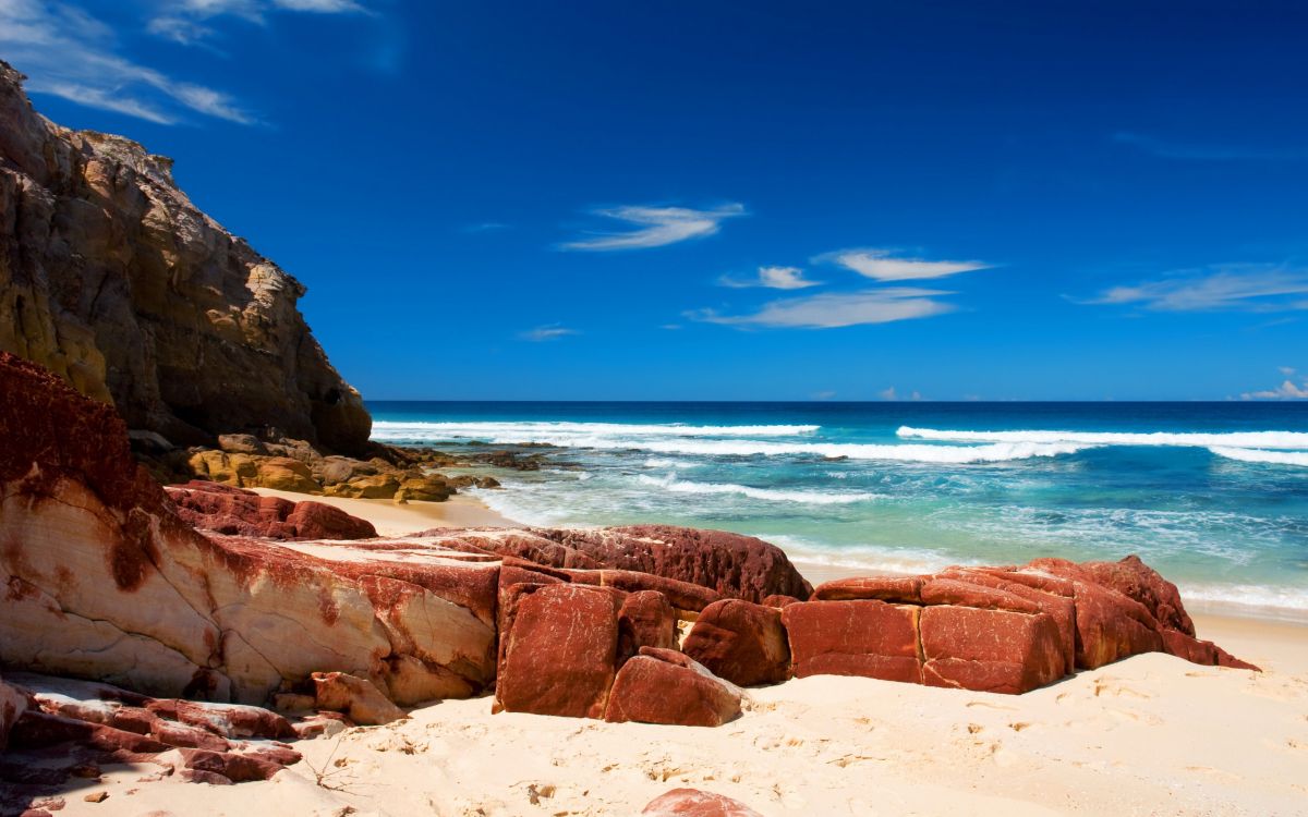 brown rock formation near sea under blue sky during daytime