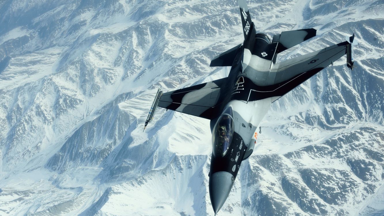 Schwarz-Weiß-Düsenflugzeug Fliegt Tagsüber Über Schneebedeckte Berge. Wallpaper in 2560x1440 Resolution