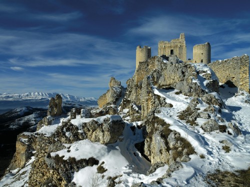 Image brown concrete building on snow covered mountain under blue sky during daytime